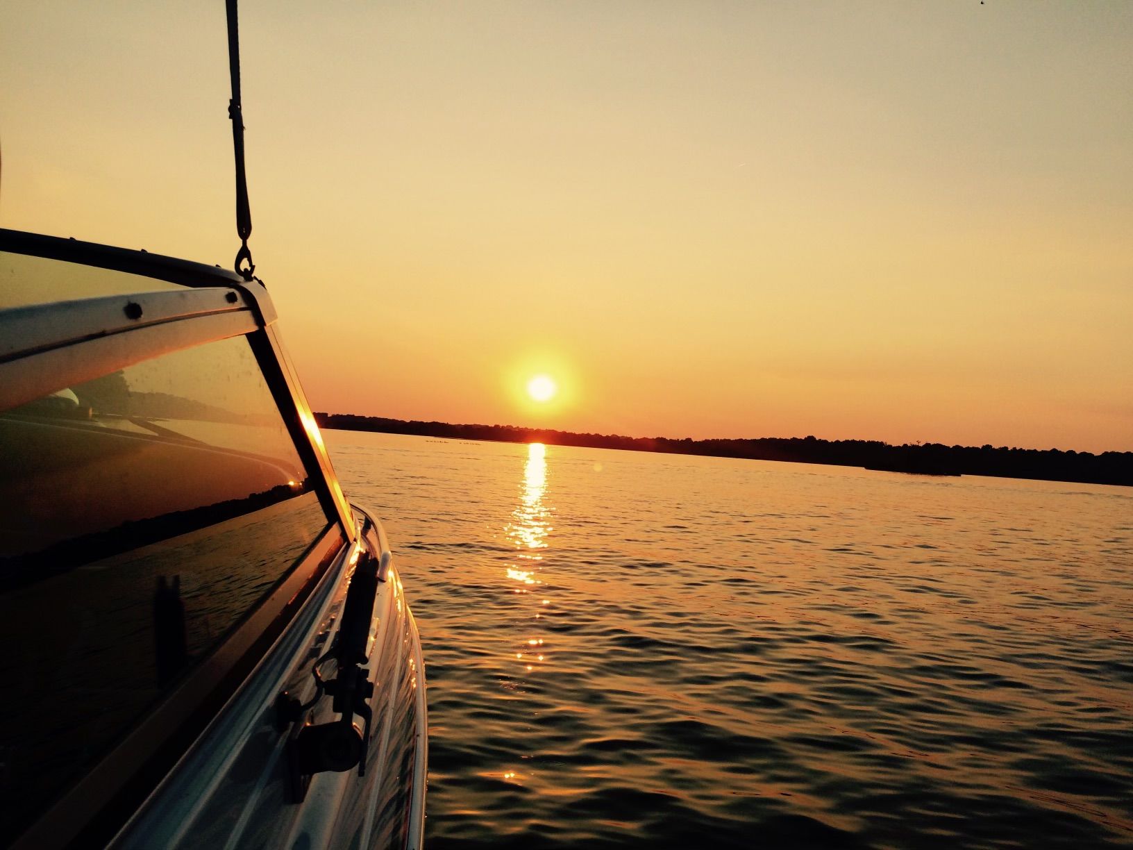 Side of boat with sun set over the lake