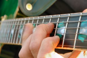 Fingers strumming a guitar.